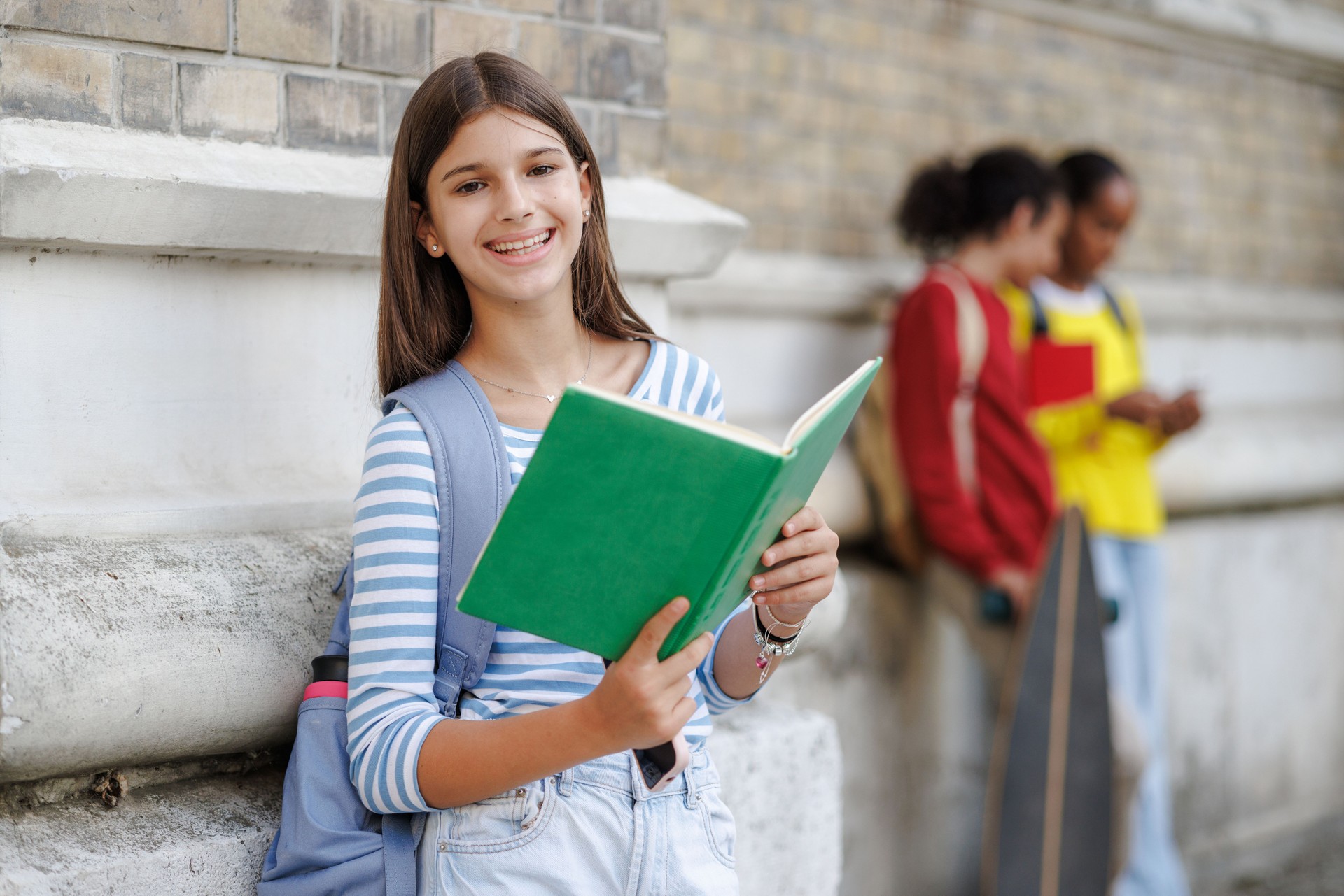 Smiling teenage girl with a book in urban setting
